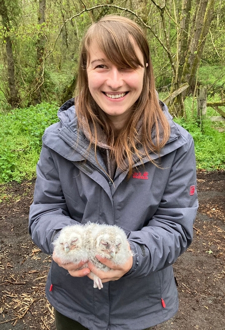 A photo of a woman holding two tawny owl chicks 