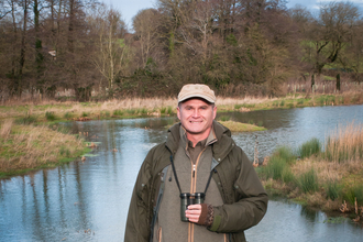 Simon King standing in front of a pond