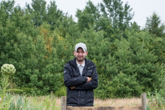 John stands besides a gate on a reserve