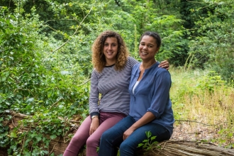 Juliet and Amy sit together on a fallen tree