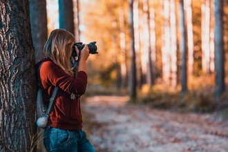 Woman holding a camera in a woodland