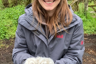 A photo of a woman holding two tawny owl chicks 