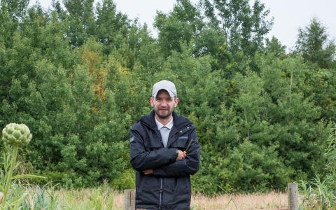 John stands besides a gate on a reserve