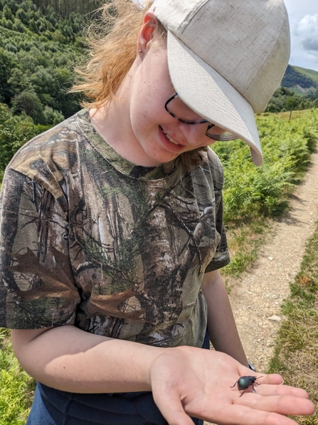 A photo of a person holding a beetle