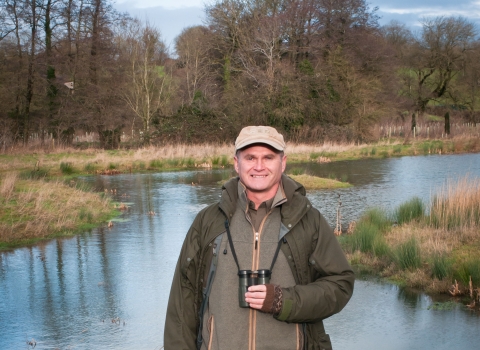 Simon King standing in front of a pond
