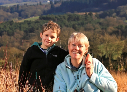 Kati and her son sat in a field with woods in background